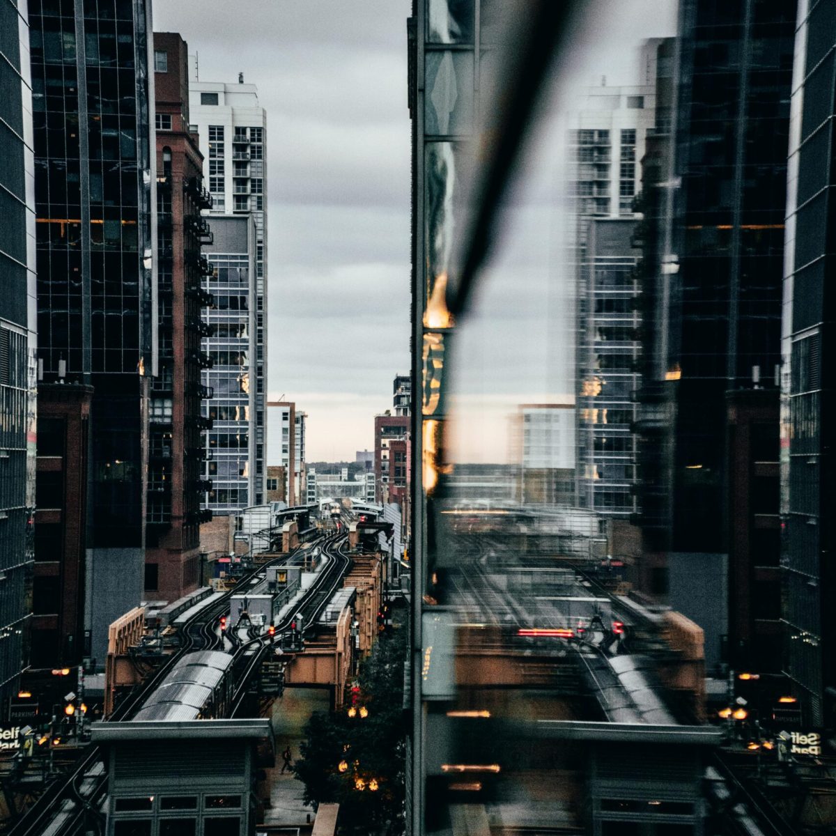 View of Chicago's elevated train with city reflections at twilight.
